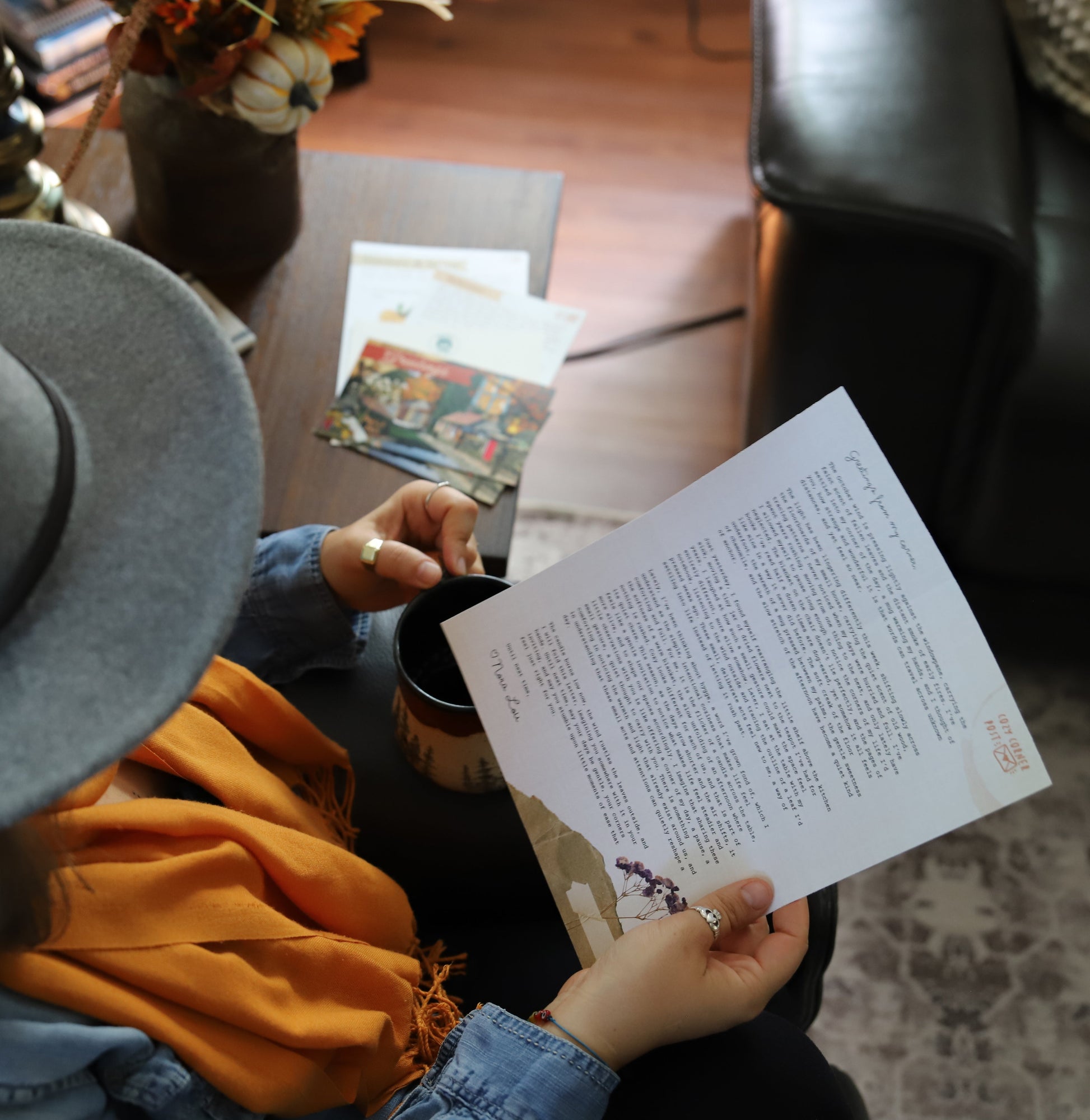 Person wearing a hat and holding a letter in a cozy indoor setting