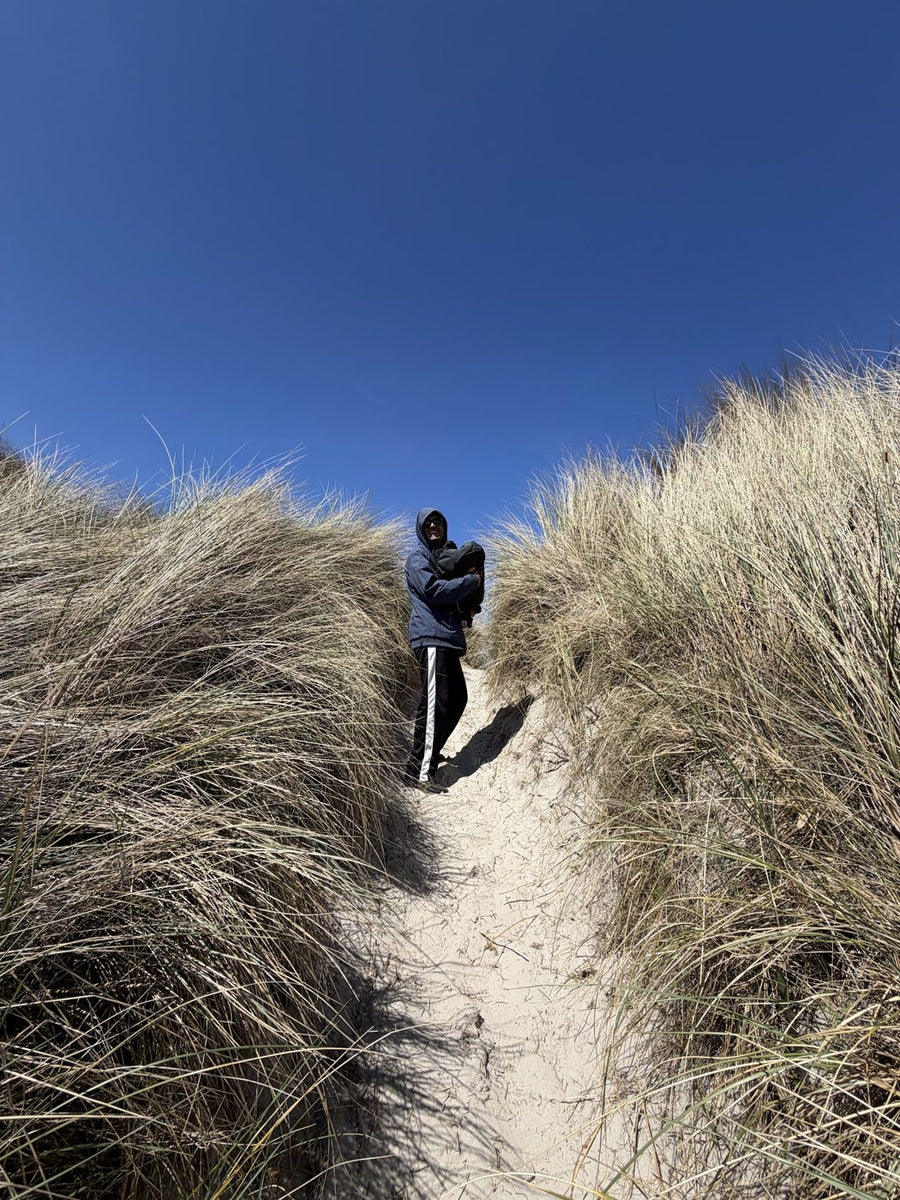 A person walking a sandy path through tall dune grass