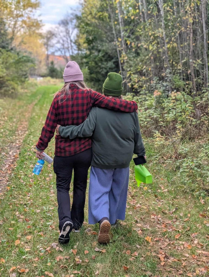 Two people walking arm in arm on a leafy autumn path