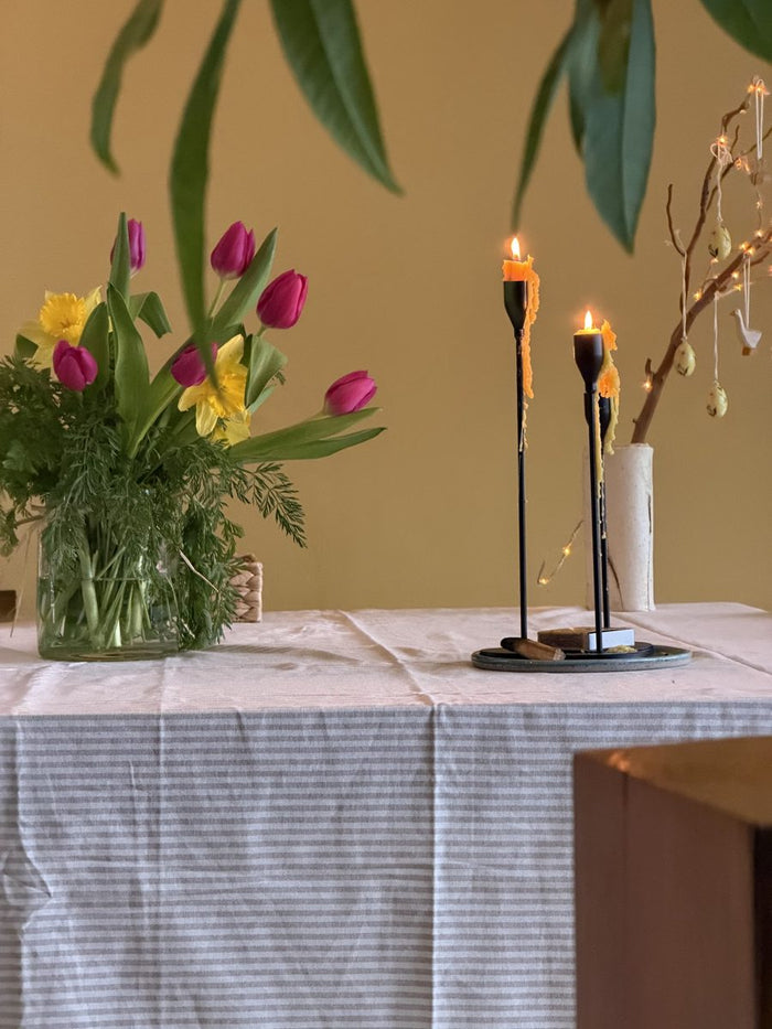 Tulips in a vase beside lit candles
