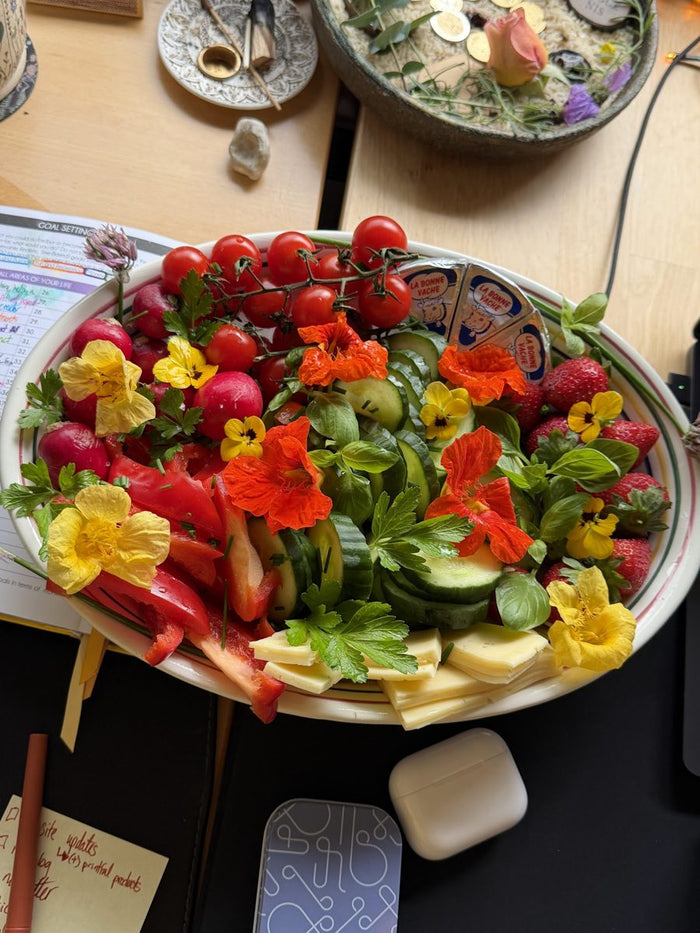 A platter of colourful food and edible flowers on a table