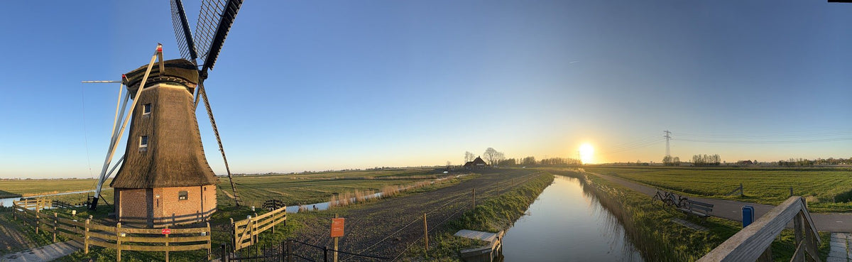 A windmill on the Frisian polder at sunset, wide view