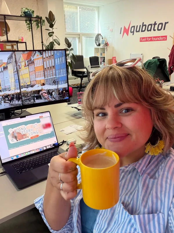 Alex at her desk at Inqubator, smiling over a yellow mug